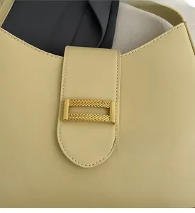 Detailed macro view of the beige matte leather handbag with a gold rectangular metal buckle