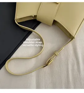 Detail of yellow leather shoulder bag showing adjustable strap and gold metal buckle
