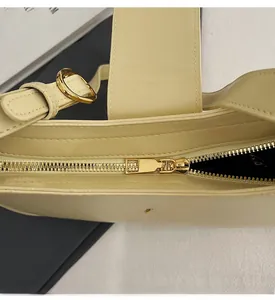 Close-up of golden metal zipper hardware and smooth stitching on cream leather bag
