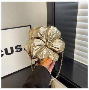 Close-up of golden flower-shaped acrylic evening clutch with textured metallic finish
