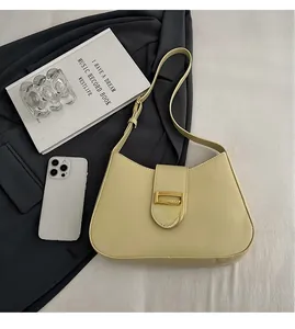 Close-up of bright yellow shoulder bag with gold metal buckle on a stylish desk setting