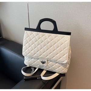 Detailansicht der cremeweißen Stepptasche mit silbernem Herzschloss und schwarzem Handgriff
