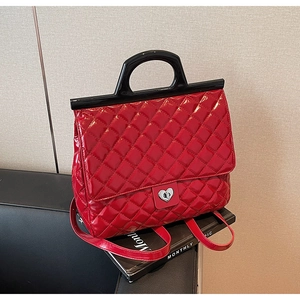 Details einer roten Stepphandtasche mit silbernem Herzschloss und schwarzem Griff