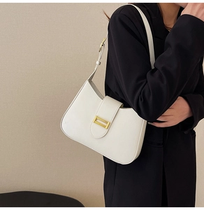 Minimalist beige leather underarm bag with gold buckle styled on a model's shoulder