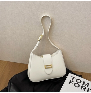 Detail view of white half-moon shoulder bag with sleek leather and gold rectangular buckle