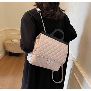 Detail der hellrosa gesteppten Handtasche mit Herzschloss und schwarzem Griff am Model