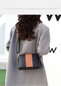 Bolso pequeño cuadrado bandolera con diseño en contraste y barra metálica frontal