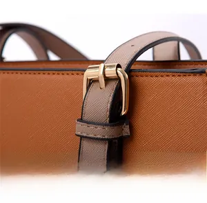 Detalle de textura de cuero Saffiano y hebilla de metal dorado en bolso tote marrón