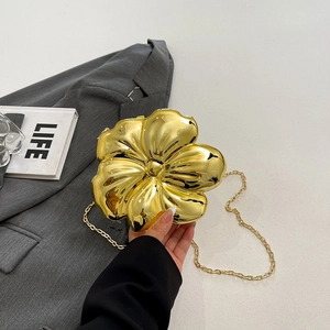 Chic gold flower-shaped acrylic clutch bag with metallic chain on a grey suit jacket