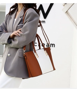 Détail d'un sac à main contrasté marron et blanc avec poignée ronde et boucle en métal