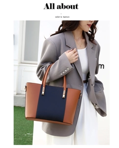 Détail du sac à main bicolore avec pièces dorées porté avec un blazer gris élégant