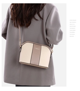 Détail d'un sac bandoulière beige tricolore avec bandoulière réglable et logo doré