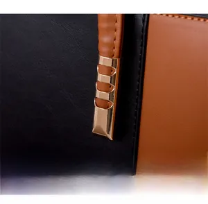 Détail de la boucle dorée renforcée reliant le cuir noir et marron sur ce sac fourre-tout
