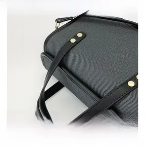 Detail of hand-woven fabric texture with leather strap and gold rivet on a mini bag