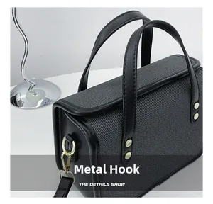 Detail showing high-quality gold metal hooks and gray canvas texture on the crossbody bag