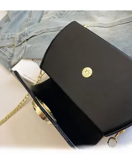 Dettaglio borsa a tracolla nera con catena dorata e chiusura magnetica elegante