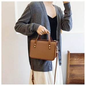 Close-up of brown patchwork crossbody bag with woven texture and gold rivets