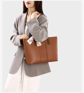 Sac fourre-tout en cuir marron avec foulard en soie sur un mannequin en costume gris