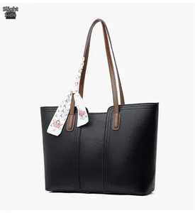 Vue latérale du sac fourre-tout noir avec foulard en soie et anse en cuir marron
