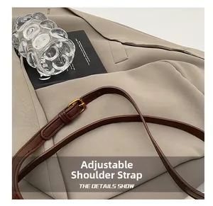 Detail of adjustable brown leather shoulder strap with a golden metal pin buckle
