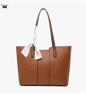 Sac fourre-tout en cuir marron avec un foulard en soie décoratif noué sur la poignée