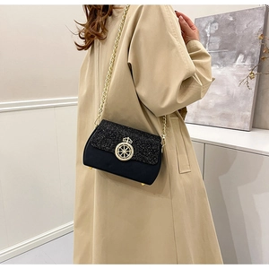 Dettaglio dell'elegante borsa a tracolla nera con patta luccicante e fibbia a corona oro