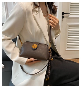 Detail of dark brown vintage crossbody bag with gold metal twist lock and decorative charm
