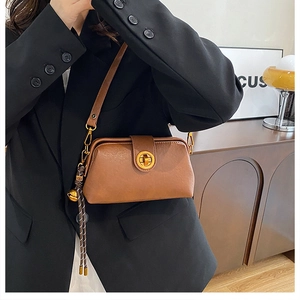 Brown faux leather crossbody bag with golden twist lock and vintage bell charm detail