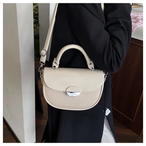Detail shot of beige patchwork saddle bag showing leather texture and silver buckle