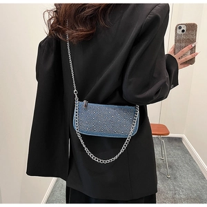 Detail of blue denim crossbody bag featuring sparkling rhinestones and silver chain strap