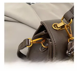 Detail of high-quality golden metal lobster clasp on a dark brown leather messenger bag