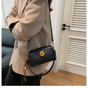 Close-up of black crossbody bag with vintage gold twist lock and bell charm detail