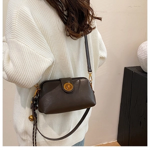 Detail of dark brown vintage doctor bag with gold hardware and bell charm on a model