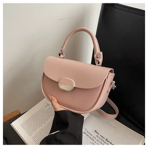 Detail of pink saddle bag with contrast textures and golden hardware on a black seat