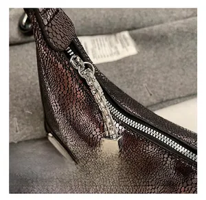 Macro view of silver zipper and square chain on dark purple snake print crescent bag