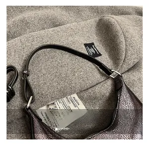 Detailed close-up of crescent bag showing faux snake texture and silver metal hardware