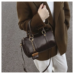 Detailed shot of a dark brown leather Boston bag with gold rivets and metallic hardware