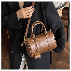 Detail view of a vintage dark brown Boston bag with a mini lock charm and gold chain detail