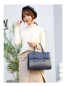 Detail of dark blue crocodile pattern handbag with glossy PU texture and metal rivets