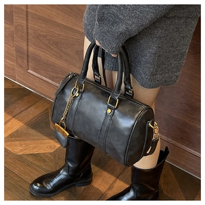 Detailed view of a retro black leather Boston bag with gold chain and hardware accents