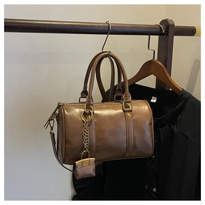 Detailed close-up of brown matte Boston bag with vintage zipper and hanging mini pouch