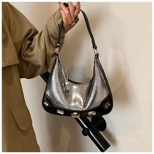 Silver crescent bag with crystal studs and black trim detail held by a model