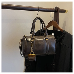 Detail of vintage Boston bag with mini purse charm hanging on a wooden rack