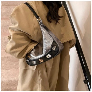 Close-up of silver snakeskin crescent bag featuring large crystal embellishments