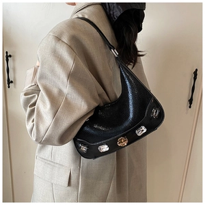 Detail of black crescent hobo bag with large crystal embellishments and sleek leather texture
