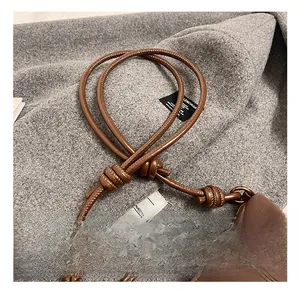 Detail of adjustable knotted strap and side stitching on brown faux leather dumpling bag