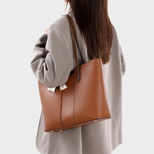 Sac cabas en cuir marron avec foulard en soie et clous dorés sur mannequin en tailleur