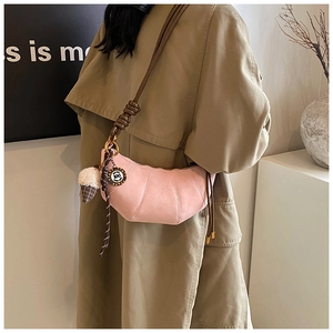 Pink dumpling crossbody bag detail with brown leather strap and decorative charm