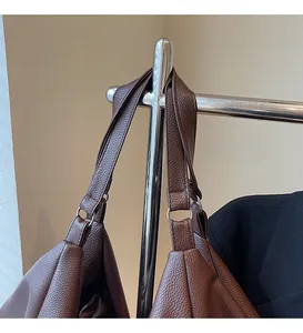 Detail of dark brown pebble leather tote bag featuring wide strap and metallic rings