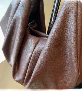 Detail of dark brown tote bag with soft lychee grain leather texture and metallic accents